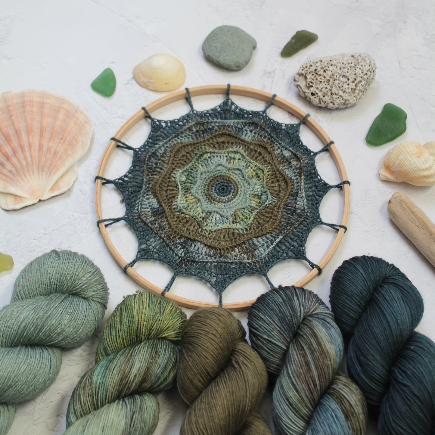 Rought Seas Mandala in blues and greens styled with seaglass and stones, and the hand dyed yarns used
