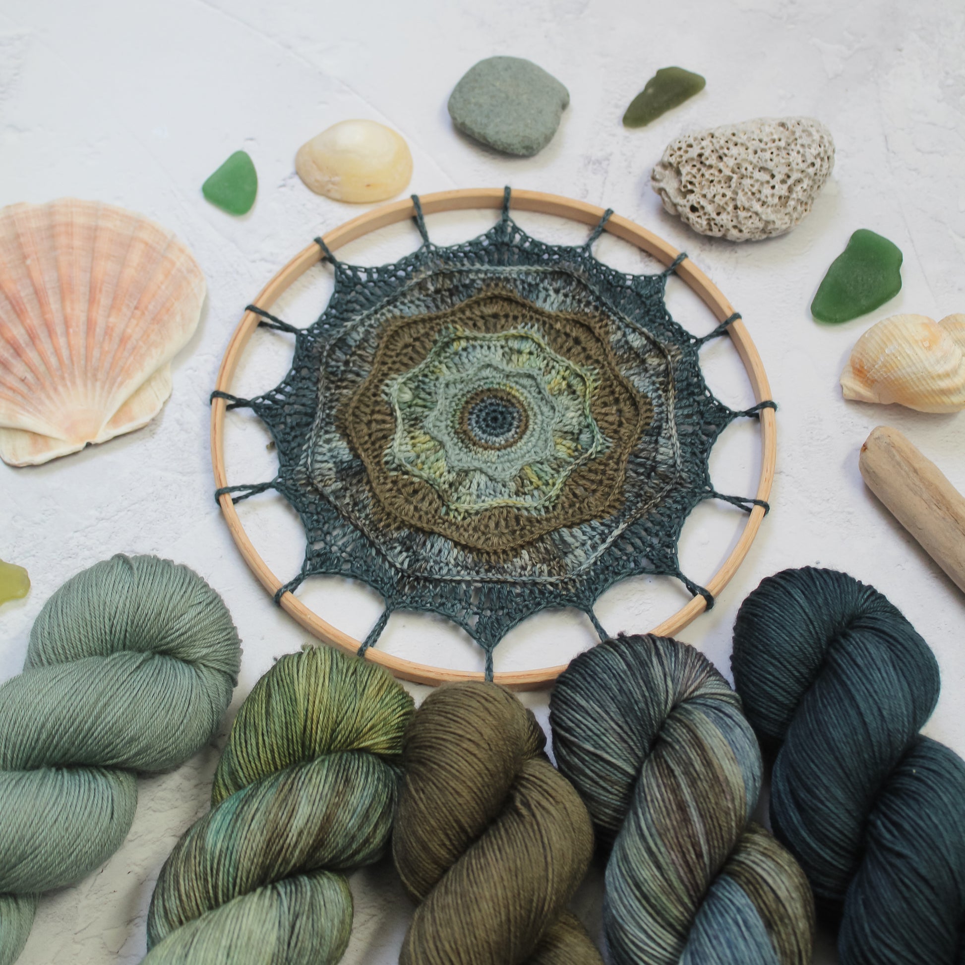 Rought Seas Mandala in blues and greens styled with seaglass and stones, and the hand dyed yarns used